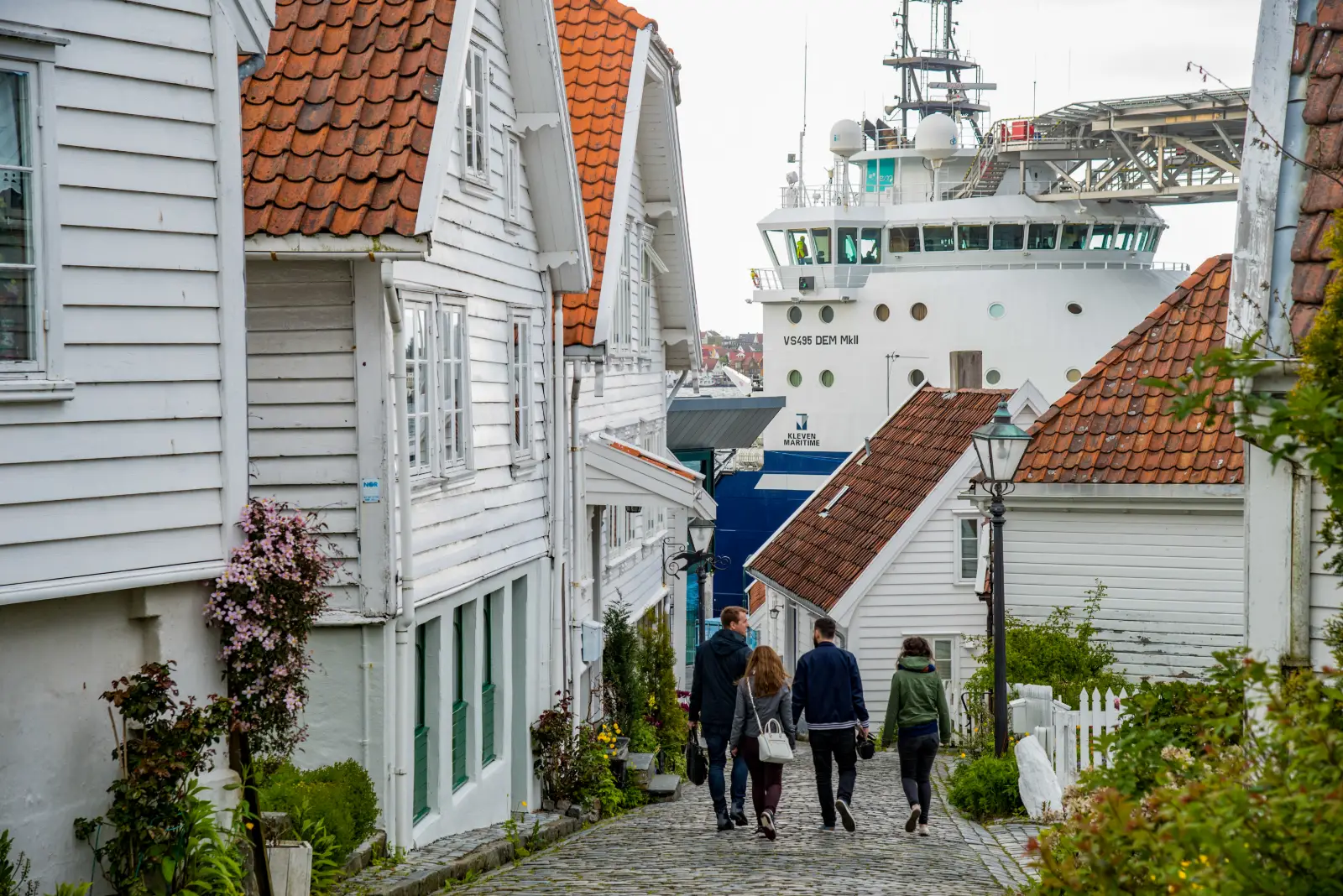 Calle entre casas blancas de Gamle Stavanger hacia el puerto