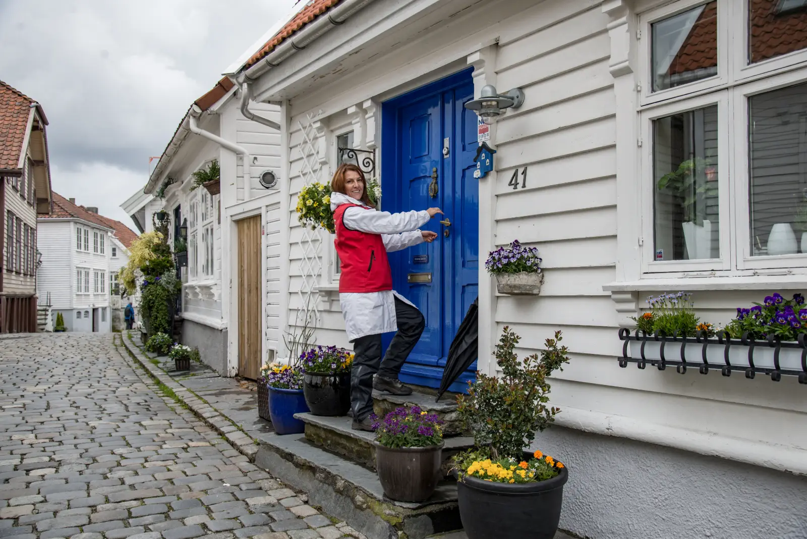 Una vecina ante la puerta azul de una casa de Gamle Stavanger