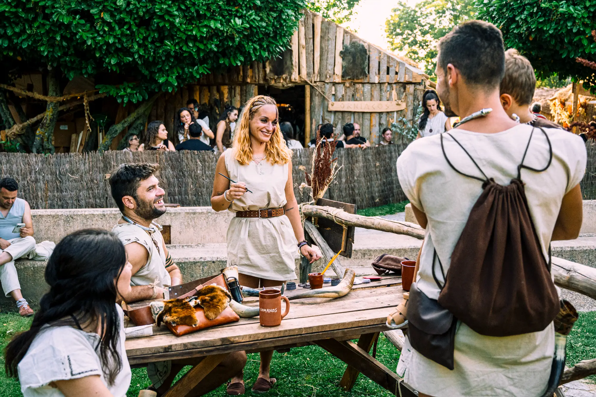 Familias conversando ante una palloza en el campamento astur