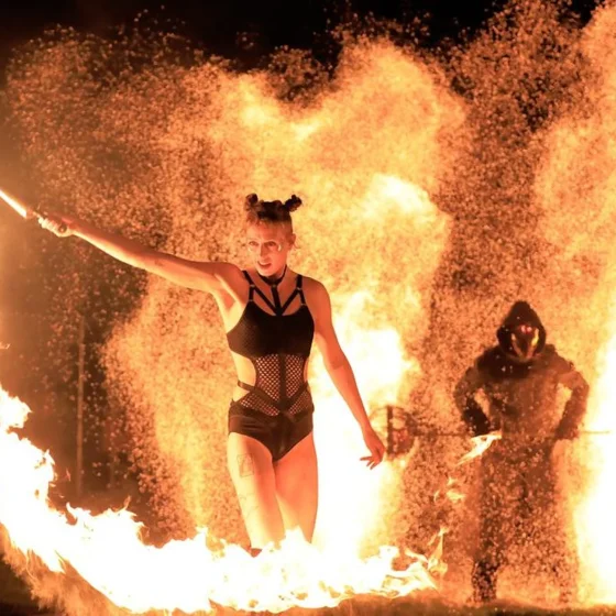 Artista de Pyro Collective con una antorcha, rodeada de llamas durante el Púca Festival de 2022 en Trim, Irlanda. © Harris PR