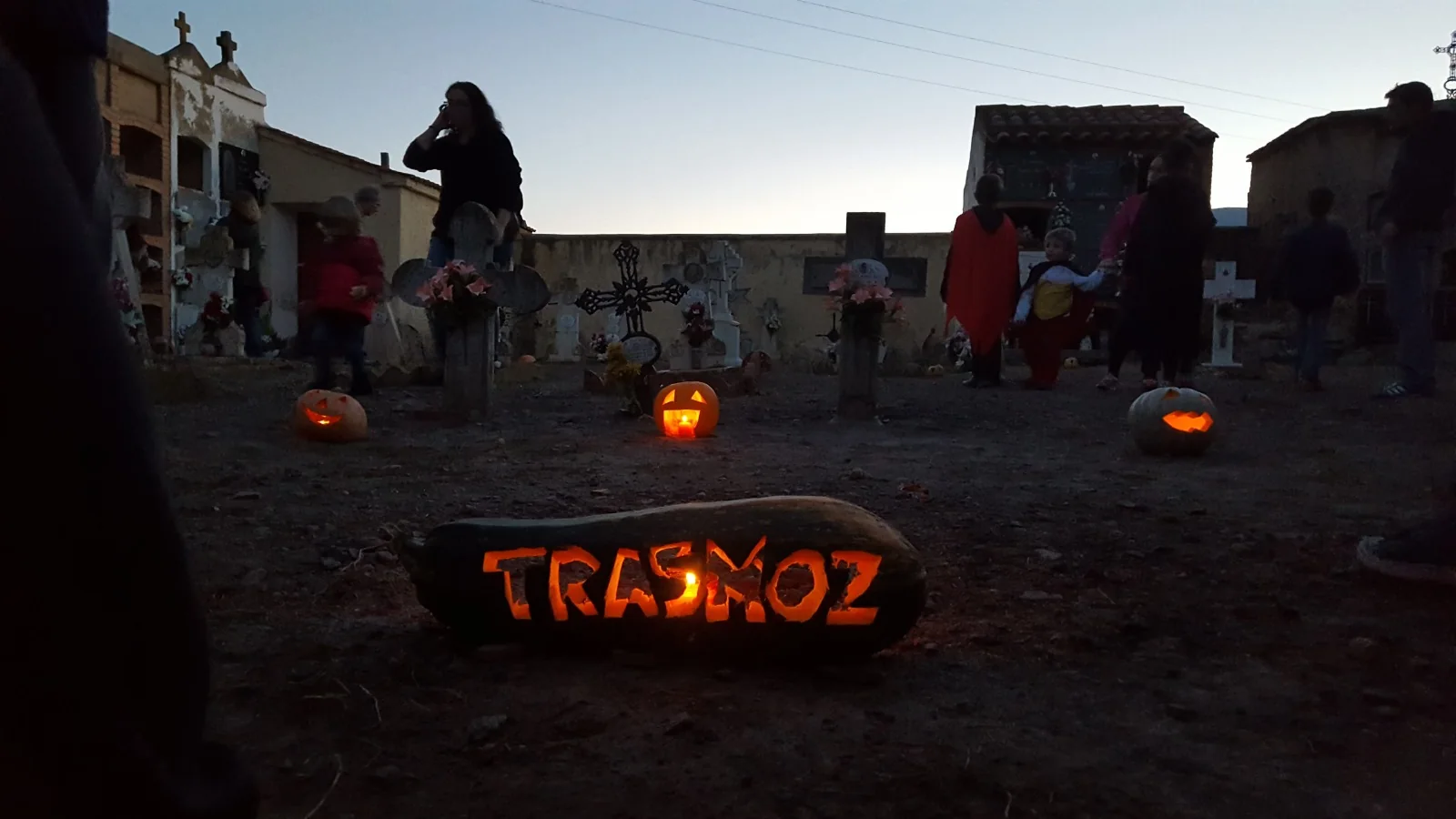 Calabazas talladas e iluminadas en una plaza de Trasmoz al anochecer.