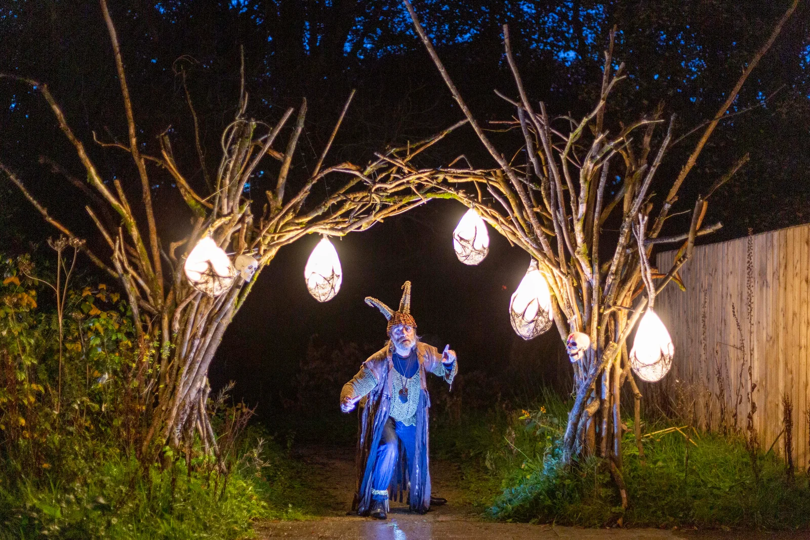 Personaje con túnica azul bajo árboles iluminados en Derry Halloween. © Lorcan Doherty Photography