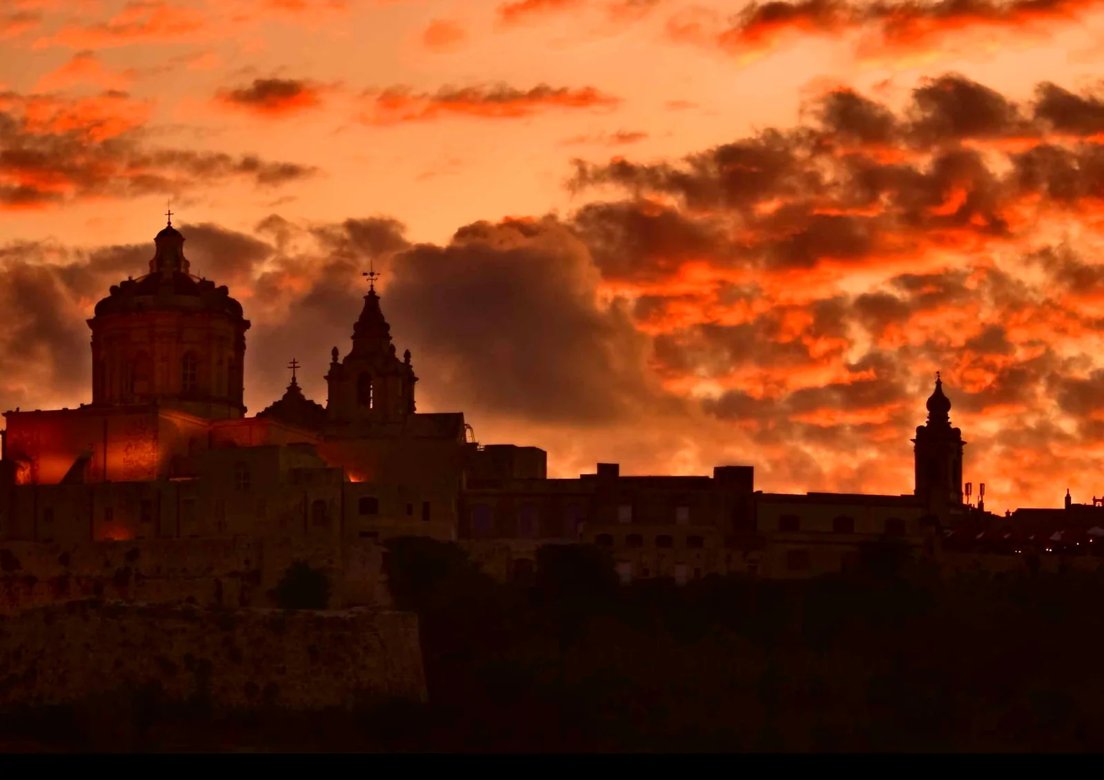 La silueta de Mdina, en Malta, bajo un cielo anaranjado al atardecer.