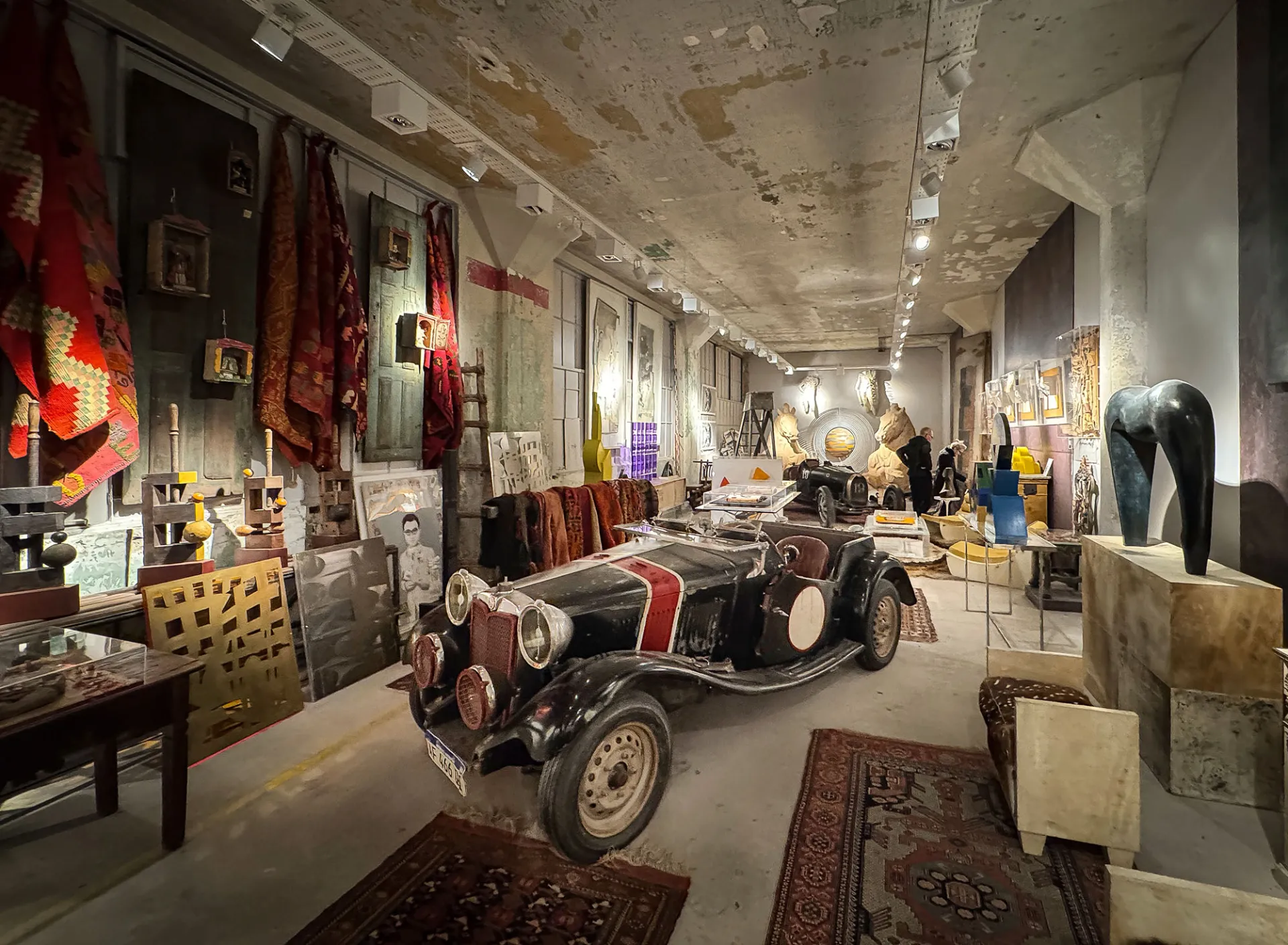 Obras de arte, objetos y un automóvil clásico en una galería de Casa FOA, Buenos Aires