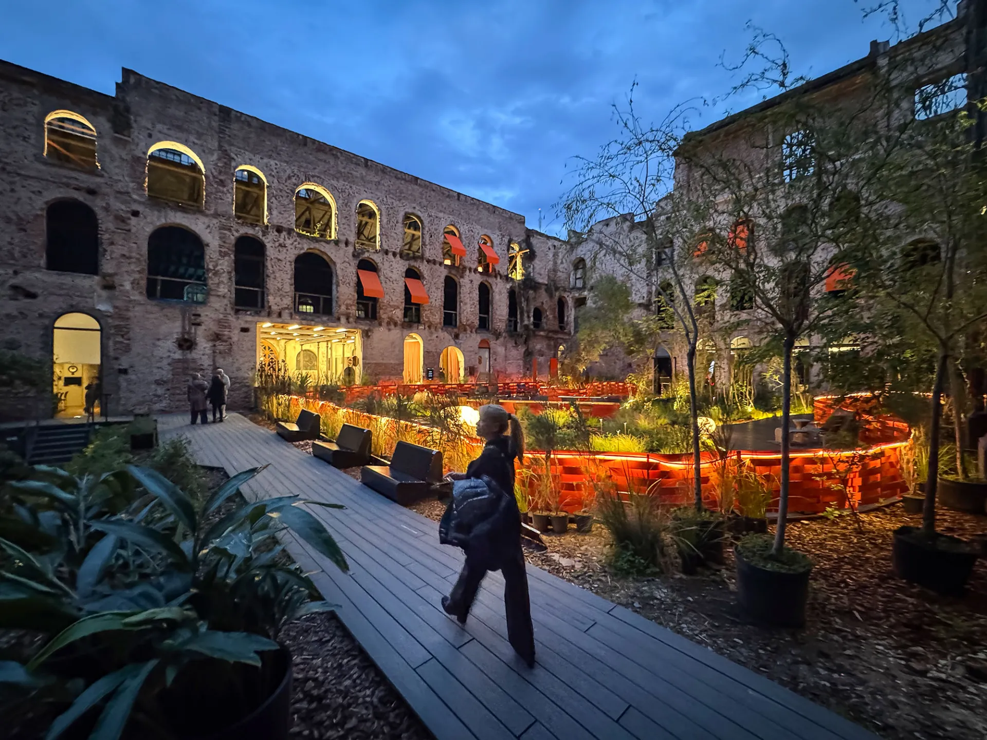 Jardín y fachadas industriales de Palacio Molina iluminados al anochecer, Buenos Aires