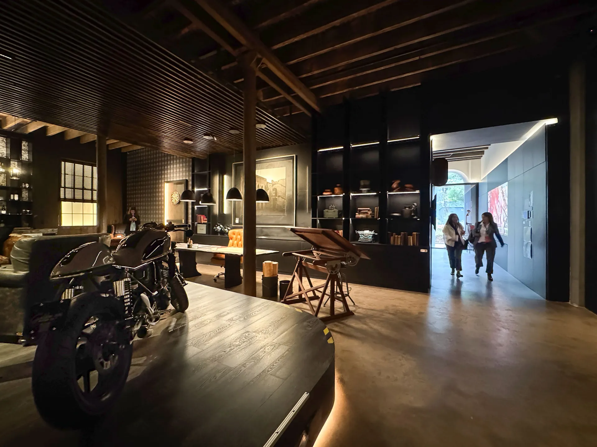 Interior de exposición con una motocicleta, mobiliario y vigas de madera, Buenos Aires