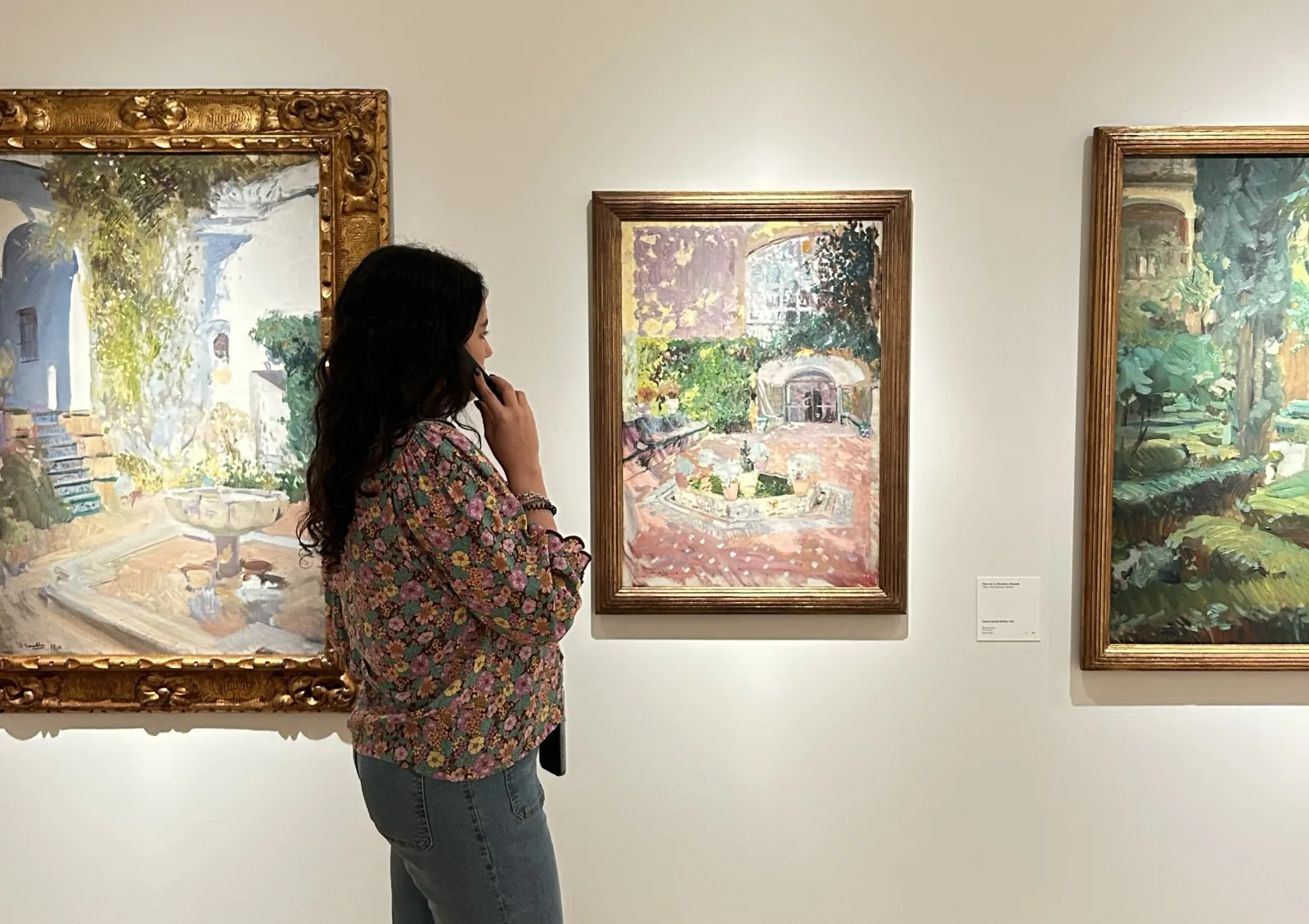 Una visitante contempla pinturas de jardines en la exposición Tras la casa del artista.